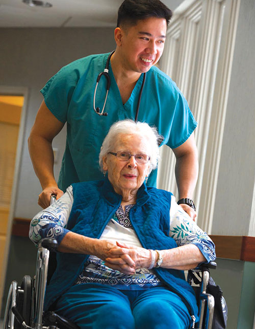 Nurse pushing elderly woman in wheelchair